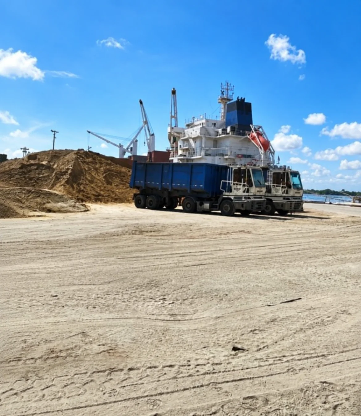 Buque y camiones en una operación de llenado para exportación de agregados